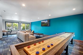 a game room with a shuffleboard table and couches